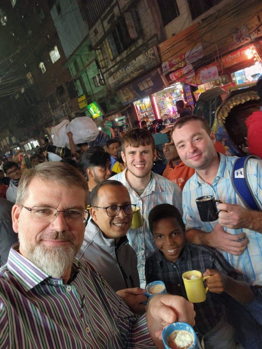 BLCC students enjoying street tea with locals in a busy Dhaka market at night