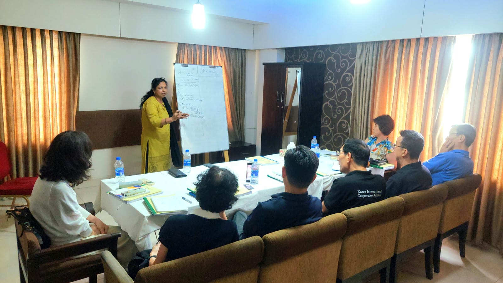 Paninna teaching a Bangla class at a whiteboard to a group of students