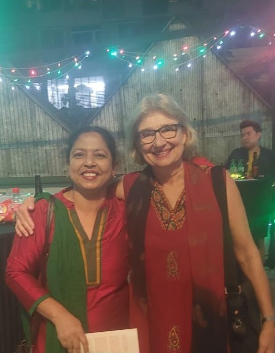 A BLCC teacher and friend smiling at an evening event with festive lights