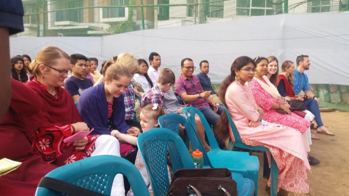 BLCC students seated with local families at an outdoor gathering in Dhaka