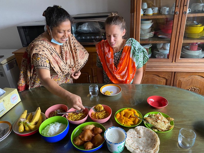 A BLCC student and host sharing a traditional Bangladeshi breakfast spread