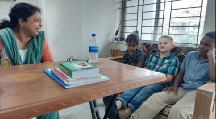 A BLCC teacher reading with three young students at a table