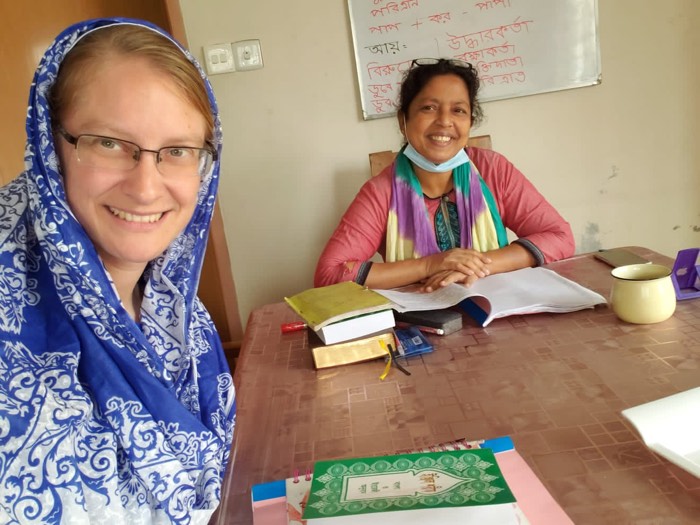 A BLCC student's Bangla notebook and study materials on the table with her teacher